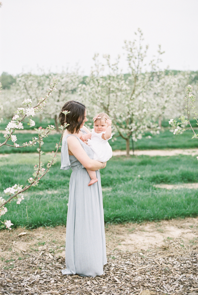 mom holding baby spring orchard